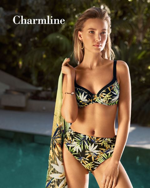 Eine Person steht in einem Bikini mit tropischem Muster an einem Pool und hält ein passendes Kleidungsstück in der Hand. Sonnenlicht fällt durch die umliegenden Bäume und wirft Schatten. In der oberen linken Ecke ist das Wort „Charmline“ zu sehen.