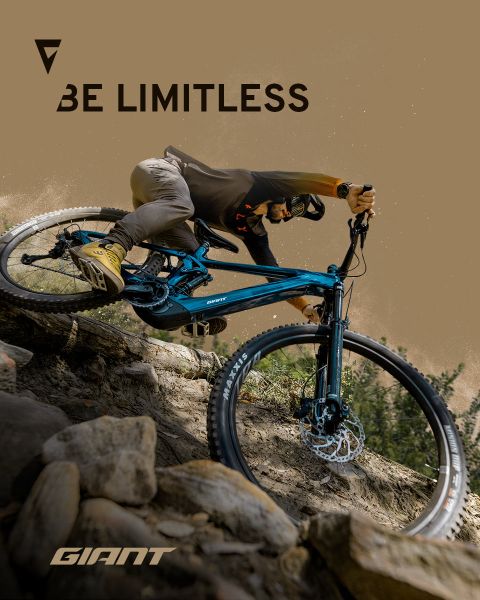 Ein Radfahrer fährt mit einem blauen Mountainbike durch felsiges Gelände. Die Worte „Be Limitless“ und „Giant“ sind auf dem Bild zu sehen. Der Fahrer trägt Helm und Radsportbekleidung, was Abenteuer und Freiheit auf dem Trail unterstreicht.