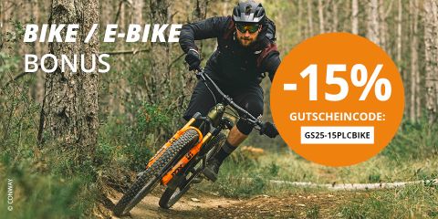 Eine Person mit Helm fährt mit einem Mountainbike einen Feldweg in einem Wald entlang. Es gibt einen großen orangefarbenen Kreis mit einem Text, der einen 15 %-Rabattcode für Fahrräder oder E-Bikes anbietet.
