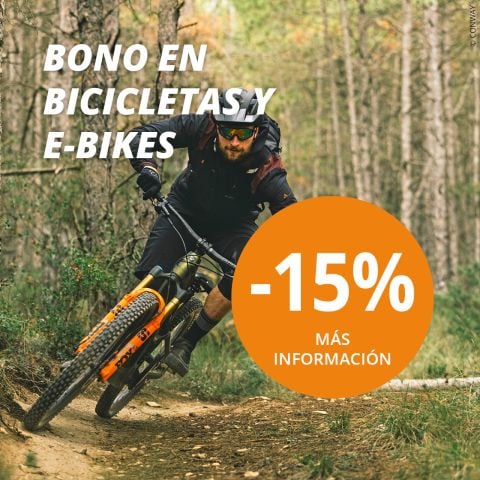 Un hombre monta en bicicleta de montaña por un sendero forestal. El texto de la imagen anuncia un 15% de descuento en bicicletas y E-Bikes con "BONO EN BICICLETAS Y E-BIKES" y "-15% MÁS INFORMACIÓN" en un círculo naranja.