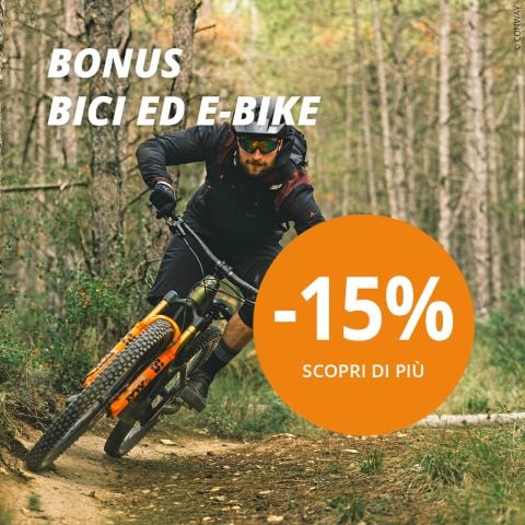 Un uomo va in mountain bike su un sentiero nel bosco. Il testo recita "BONUS BICI/E-BIKE" e un grande cerchio arancione dice "-15% SCOPRI DI PIÙ". La scena pubblicizza uno sconto su biciclette o e-bike.