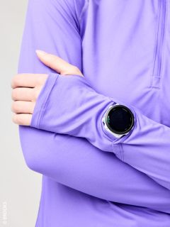 Eine Person in einem lilafarbenen langärmeligen Hemd verschränkt die Arme und trägt eine runde schwarze Smartwatch über dem Ärmel.