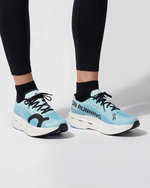 Eine Person, die gelb gestreifte Socken und weiße Laufschuhe trägt, läuft auf einem Feldweg, der von Gras und kleinen Pflanzen umgeben ist. Nur die Unterschenkel und Füße sind sichtbar.